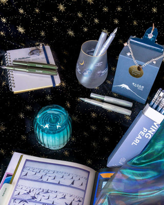 a collection of metallic and blue stationery items on a black backdrop