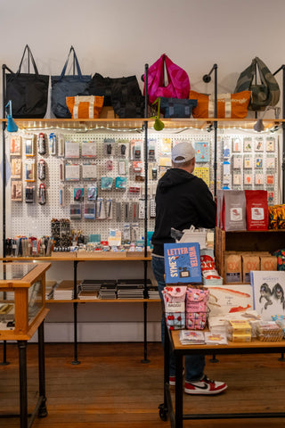 a person looking at a wall of stickers and bags inside of a store