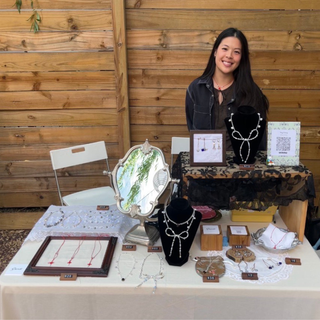 Artist Gunli standing at a table with her jewelry spread out on display