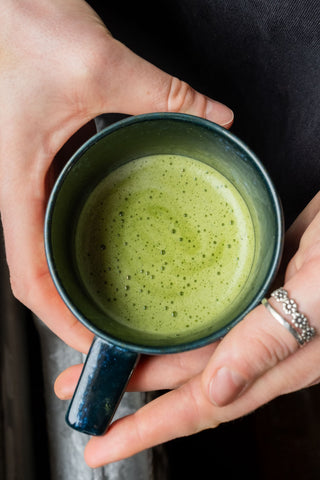 a mug of matcha in someones hands