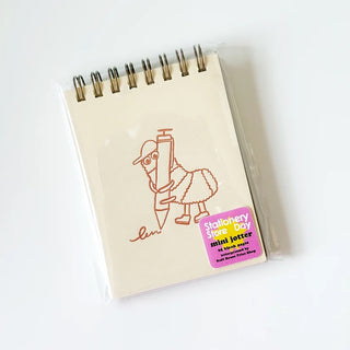 Beige mini notepad with spiral binding and line-art character on cover