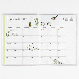 A6 monthly planner open to January 2027 calendar with frog character stickers