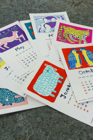 Set of 2027 monthly stand calendar pages with colorful animal illustrations, fanned out
