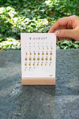 Desk calendar stand with August page and moon phase icons
