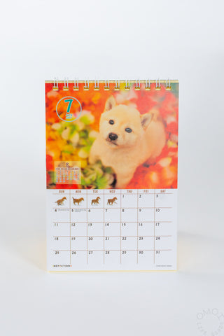 Desk calendar with Shiba Inu puppy cover, spiral rings, monthly grid.
