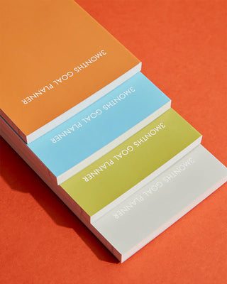 Stacked 3-month goal planners with multicolor covers, title visible on spines