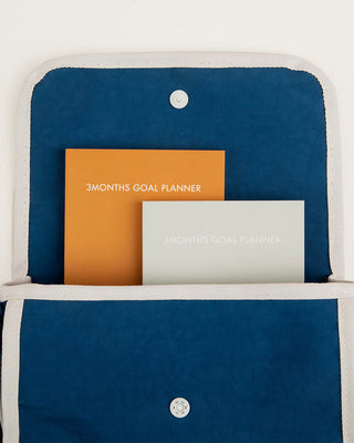 Blue planner pouch with two 3-month goal planner inserts in orange and white