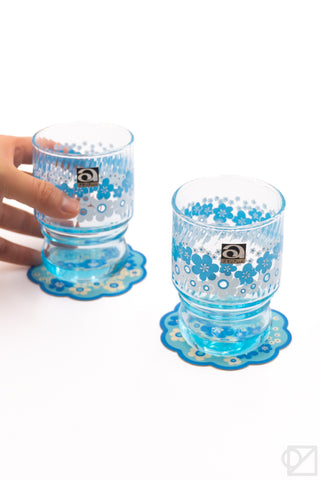 Blue floral retro stacking glass set: hand holds a cup over its coaster plate
