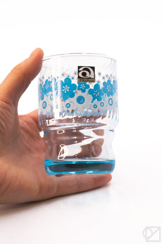 Blue floral retro stacking glass cup held in hand, showing clear body and base