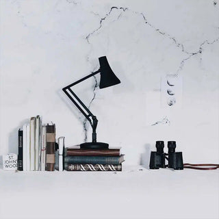 Carbon black mini desk lamp on a tabletop with conical shade and adjustable arm