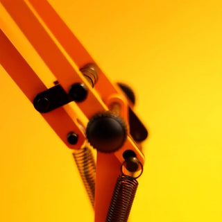 Close-up sunburnt orange lamp arm with black hinge and spring details