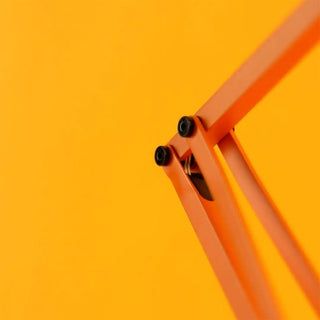 Close-up sunburnt orange adjustable lamp arm with black mounting screws