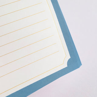 Close-up of blue letter stationery corner with gold lines and decorative border frame