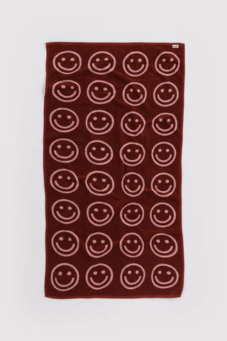Dark maroon bath towel with white smiley face pattern and corner tag