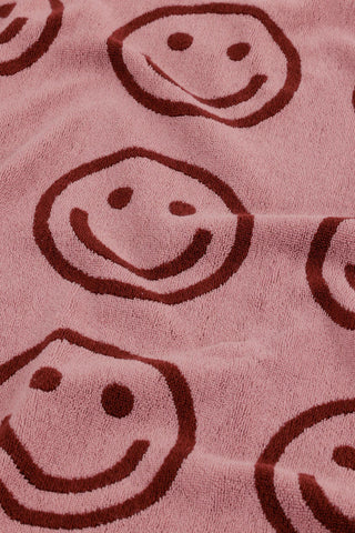 Blush bath towel close-up with brown smiling face print