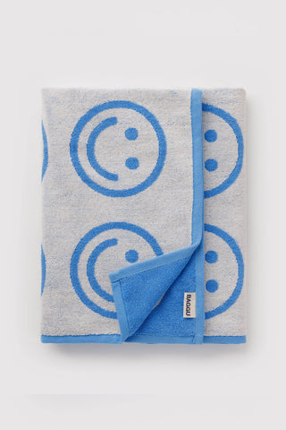 Folded sky blue bath towel with smiley pattern and small sewn brand label