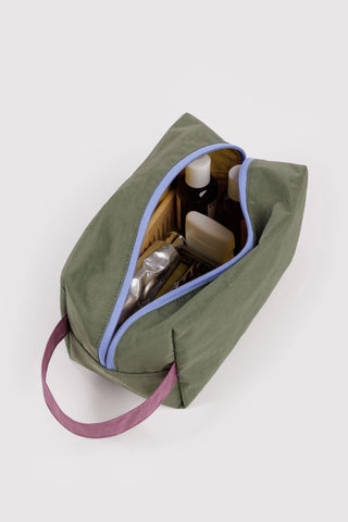 Olive toiletry bag open with yellow interior and blue-trim zipper, showing bottles