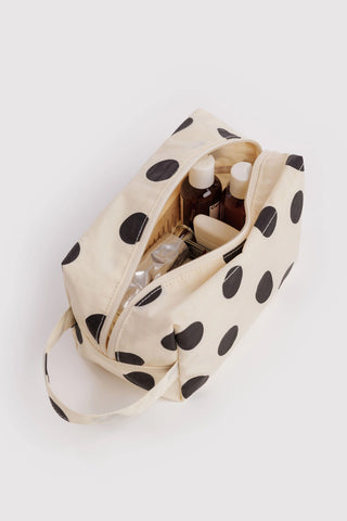 Opened cream polka dot dopp kit showing organizers and toiletry bottles inside