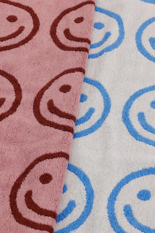 Pair of hand towels close-up, smiling face pattern in blush and sky blue