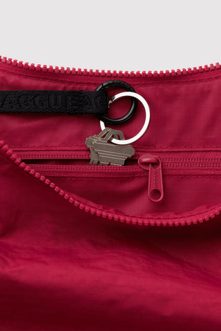Cherry nylon crescent bag close-up: zipper, logo strap, keyring clip