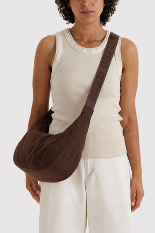Medium crescent nylon crossbody bag in coffee brown, worn over the shoulder