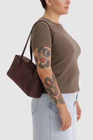 Dark brown nylon bowler bag carried by handles, side view with zip detail