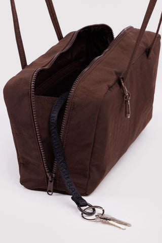 Dark brown nylon bowler bag open, showing lined interior and zipper pull keyring