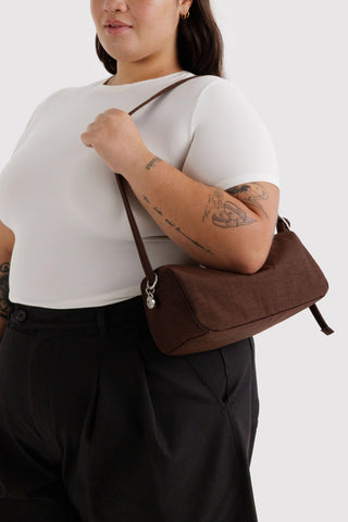 Brown nylon shoulder bag worn crossbody with zipper top and small metal clasp