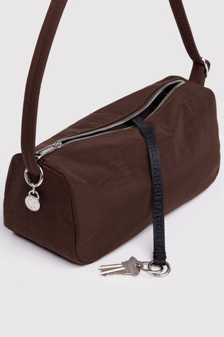 Brown nylon loaf bag detail: front zipper, keyring charm, and shoulder strap