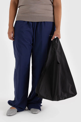 Black tote bag with short handles and roomy interior, carried by hand