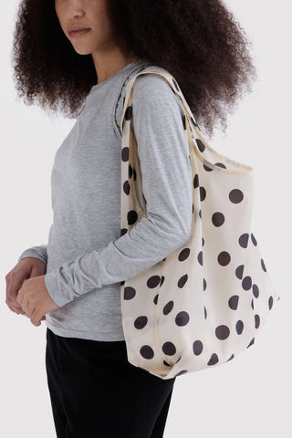 Cream polka-dot tote carried on shoulder over long-sleeve shirt