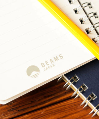 Open navy notebook with lined pages; BEAMS Japan logo visible near spiral binding.