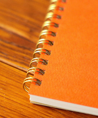 Orange BEAMS Japan lined notebook close-up of metal spiral binding