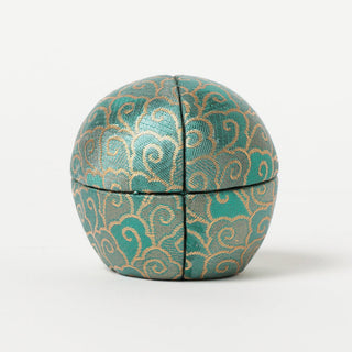 Round teal patterned Daruma-style figure with stitched panel seams