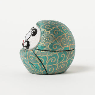 Teal fabric Daruma-style figure with embroidered angry eye and swirl pattern