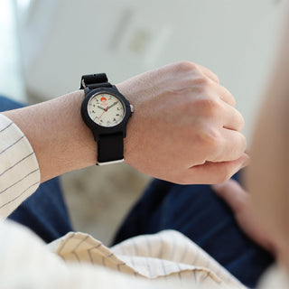 Black wristwatch on hand with black strap and cream dial, casual wear