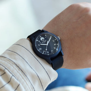 Navy wrist watch with round dark dial, gold-toned hands, and fabric strap
