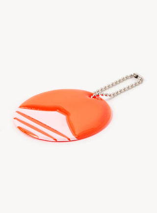 Orange circular reflector keychain on silver bead chain, angled side view