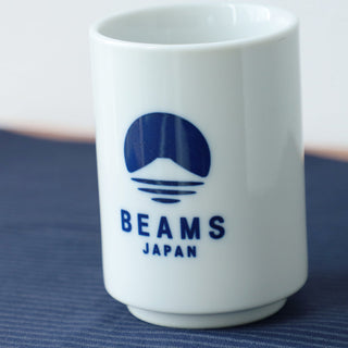 Close-up of white sushi cup with blue BEAMS Japan logo.