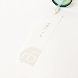 Close-up of wind chime paper tag with red logo and handwritten text