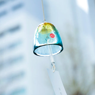 Blue glass bell wind chime with gold cap, red emblem, and hanging paper tag
