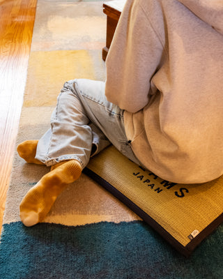 Orange-bordered BEAMS JAPAN logo cushion on rug, corner and text visible