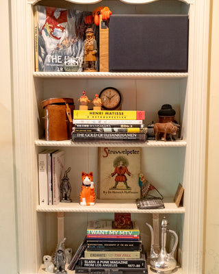 Orange ceramic fortune cat on shelf with blue collar and gold bell