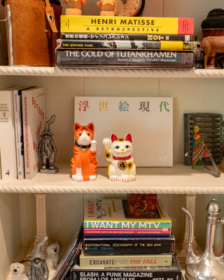 Shelf with books and decorative items including a cat-shaped object and a small statue.