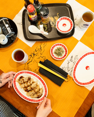 Dinner table with food, drinks, and cutlery on a decorative tablecloth.