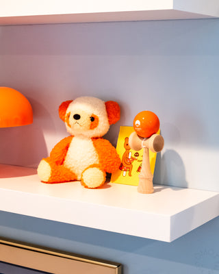 Wooden kendama display on shelf with orange ball and natural wood handle and cups