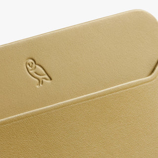 Close-up of mustard card slip with engraved bird logo and textured leather.