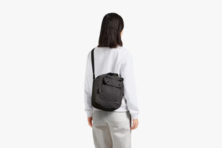 Oat cinch bucket bag worn crossbody on a person, adjustable shoulder strap visible