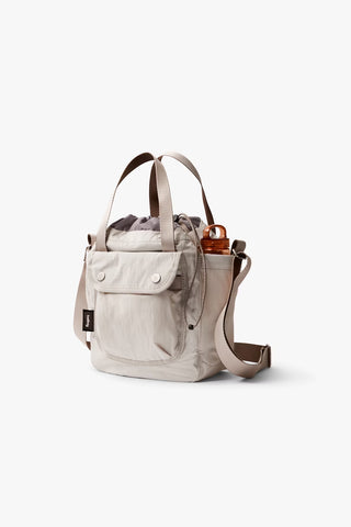 Oat cinch bucket bag with drawstring top, front pocket, and adjustable shoulder strap