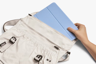 Oat light-beige messenger bag with cinch top holding a blue tablet